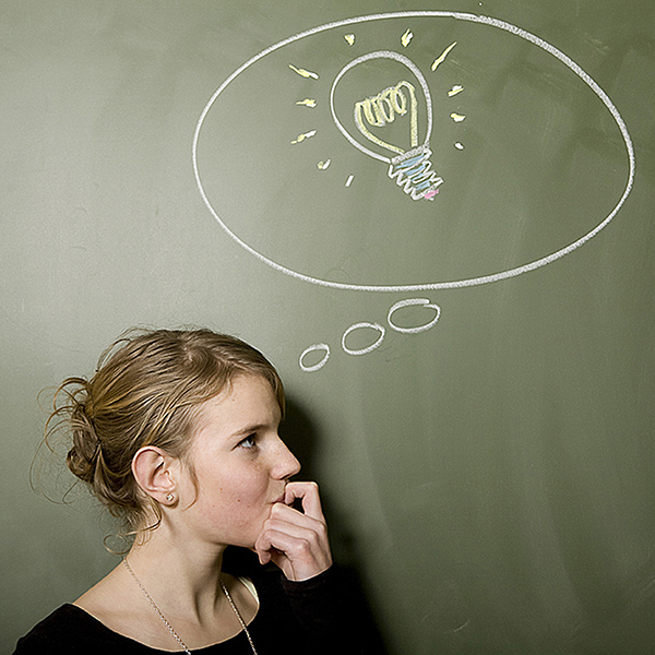 Girl stood next to chalk board with lightbulb in thought bubble drawn on