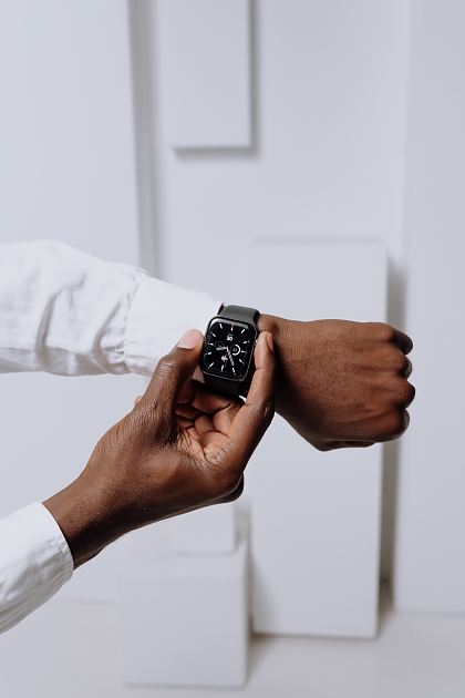 Person wearing a modern style black watch and white shirt.